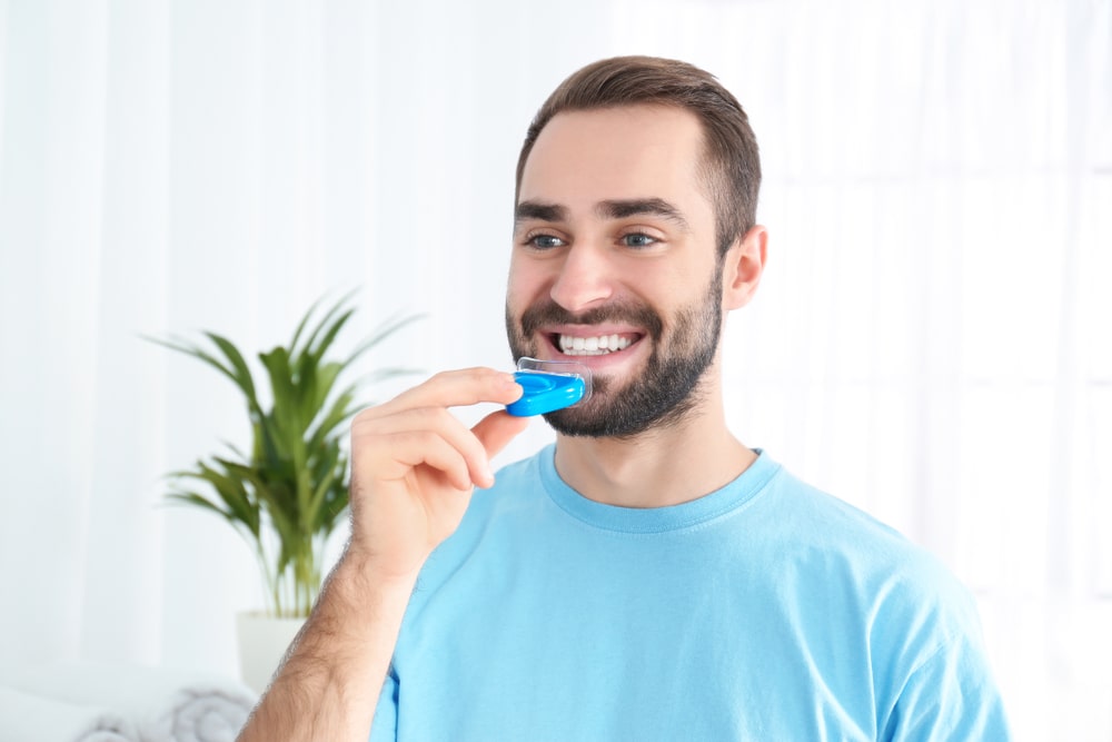 man using teeth whitening device at home